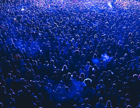 Foule compacte vue du haut baignée d'une lumière bleutée