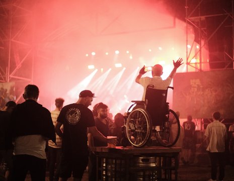 Personne en fauteuil roulant lève les bras devant la scène