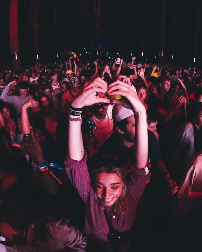 Femme fait un coeur avec ses mains dans une foule de personnes